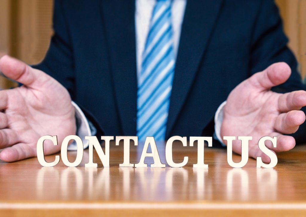 CONTACT US letters between hands and desk